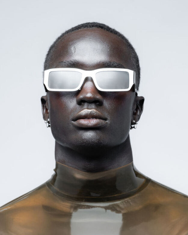 Person wearing reflective chrome sunglasses on a plain background
