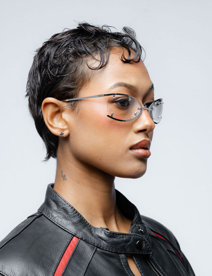 Person wearing glasses and a black leather jacket with red accents against a gray background