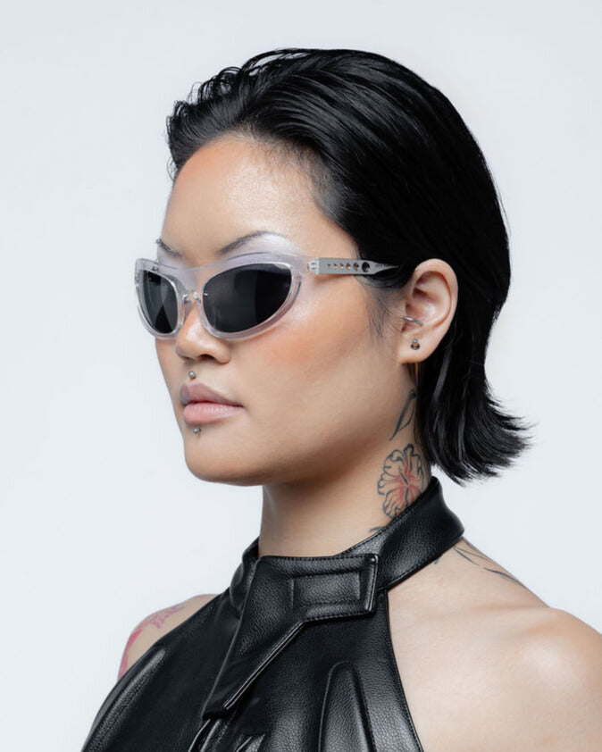 Person wearing sunglasses and a black outfit with a white background