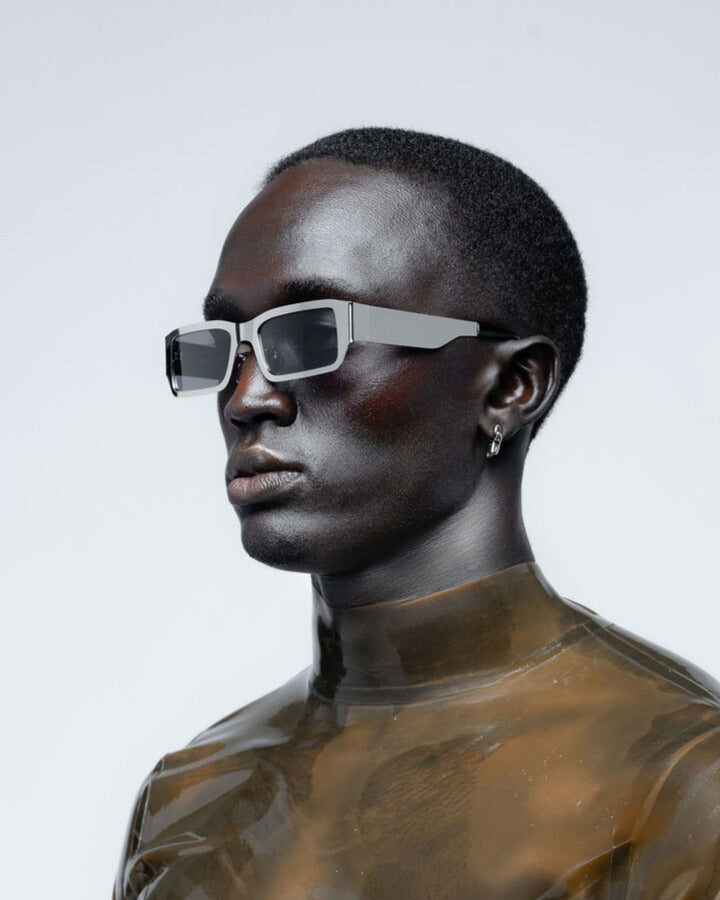 Man wearing chrome futuristic sunglasses against a light gray background
