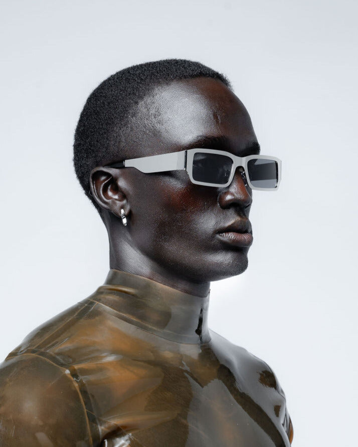 Person wearing reflective chrome sunglasses on a light gray background