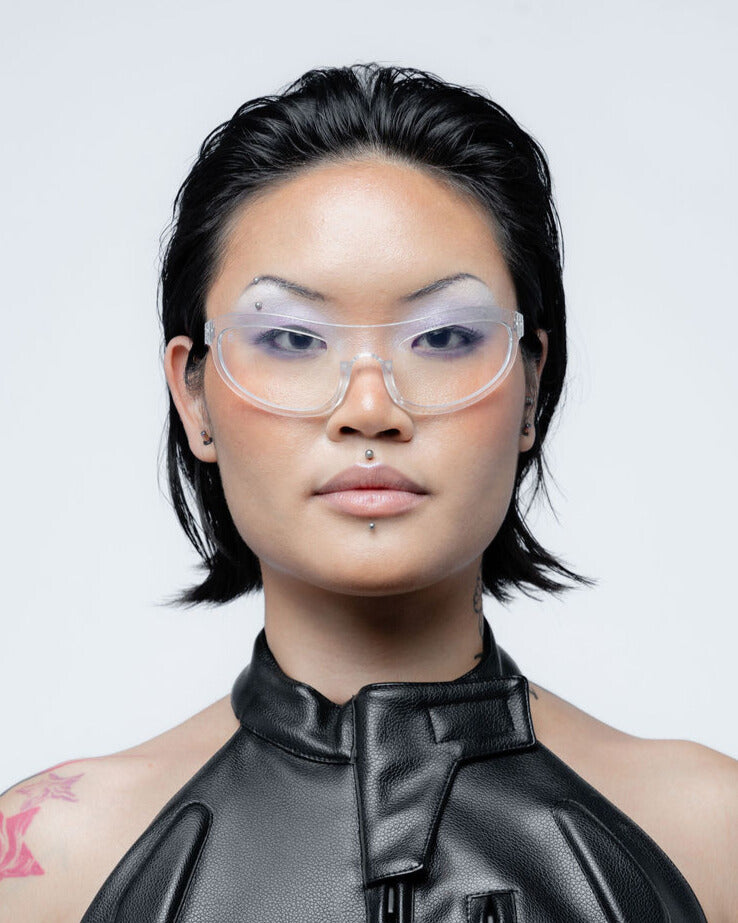Person wearing clear glasses and a black outfit with a white background