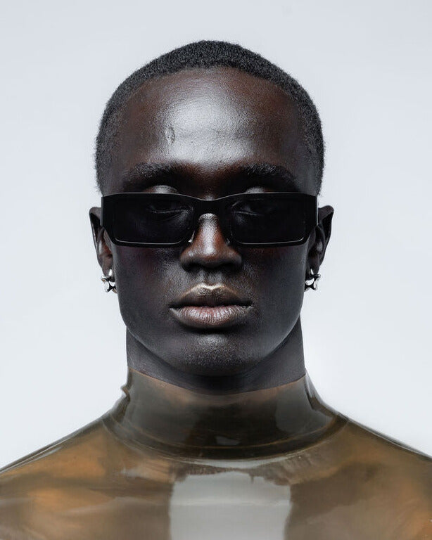 Person wearing black sunglasses with a plain background